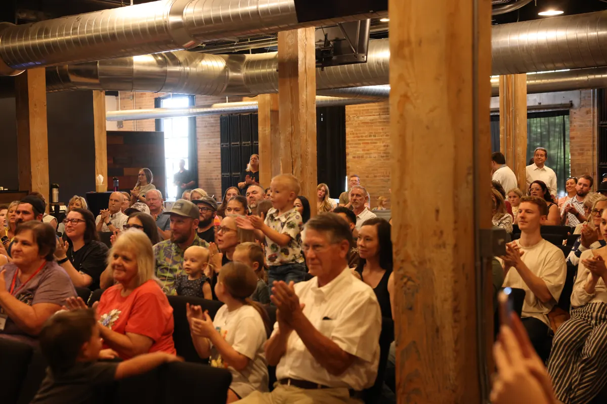 Congregation seated together, clapping during Sunday worship