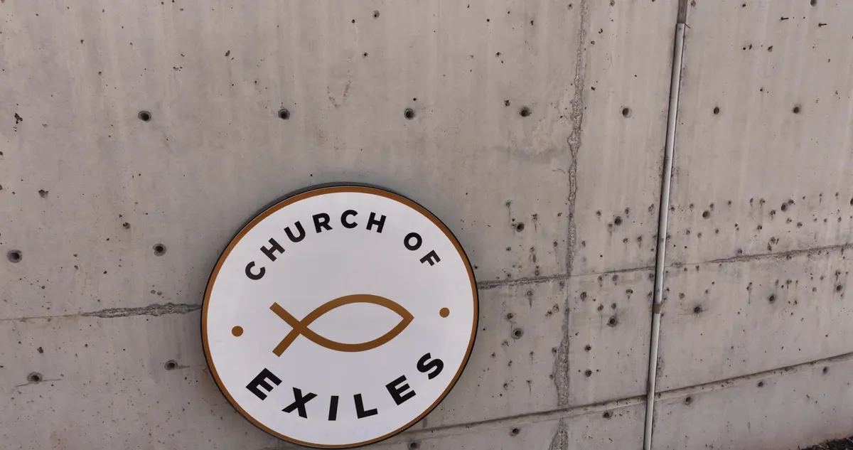 The round Church of Exiles sign on the concrete wall outside our building