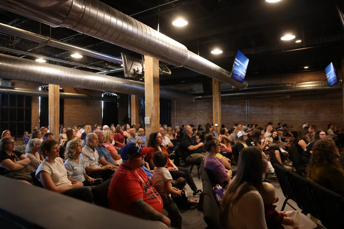 A full room of people gathered for Sunday service under warm string lights